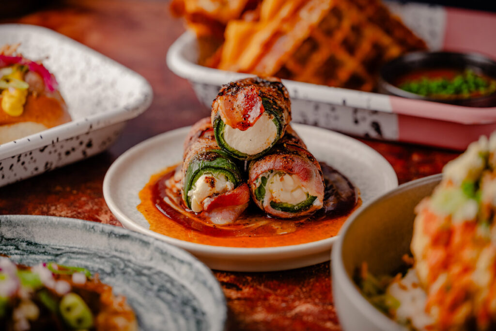 RC3-January25-FullAlbum-76 Charred and pickled jalapeños, stuffed with burnt ends, cream cheese, and herbs, wrapped in applewood-smoked bacon and topped with marshmallow BBQ sauce and Alabama white sauce.