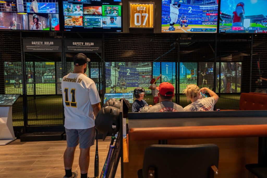 family-playing-baseball-simulator-dallas.jpg Family playing together on a baseball simulator at Batbox Dallas indoor sports entertainment venue